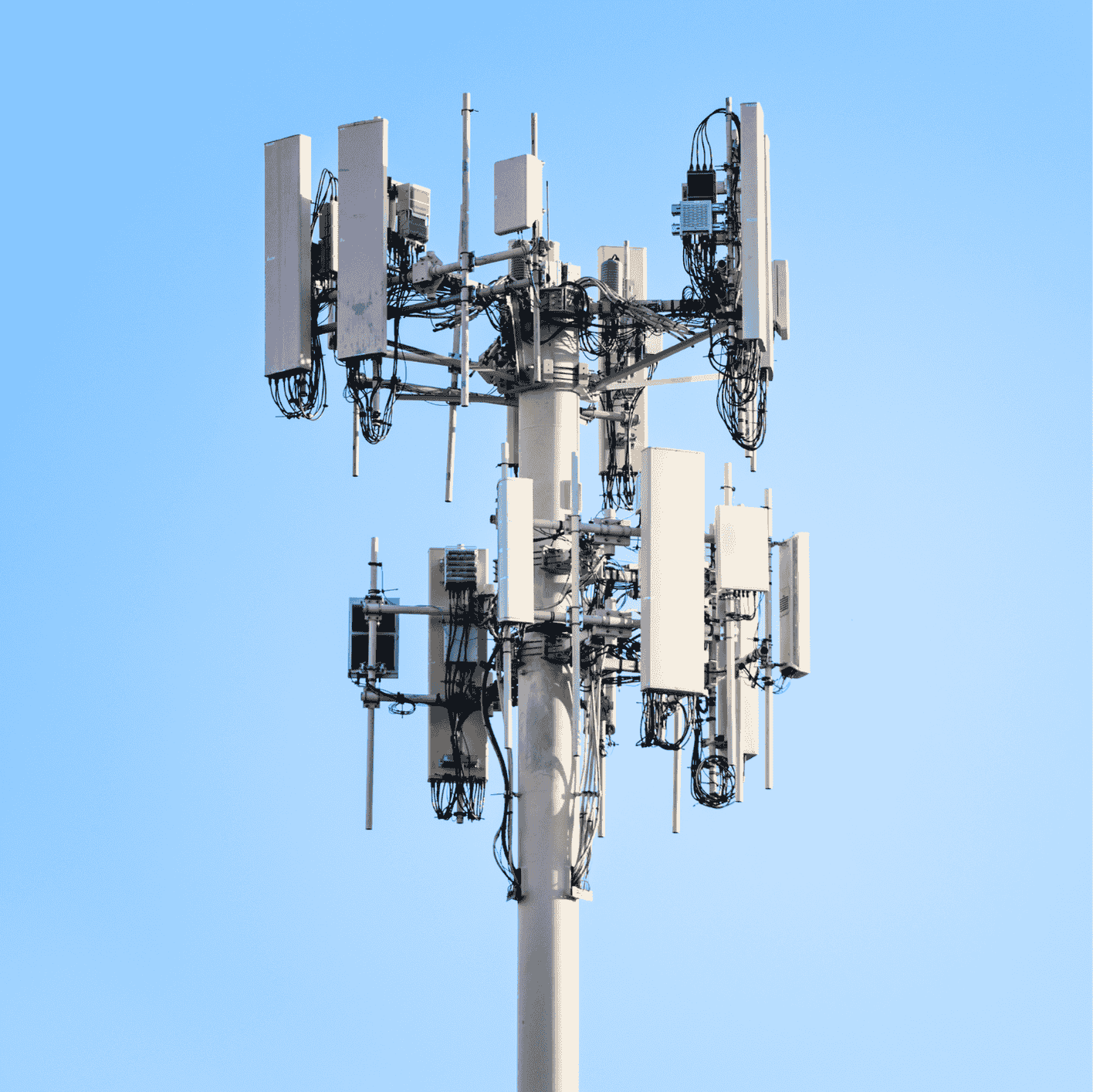 Cellular mast with multiple antenna panels against a blue sky