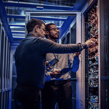 Engineers patching network cables in a data centre rack