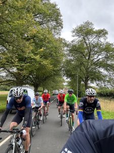 Group of cyclists riding together on a tree-lined road during the Tour de BT